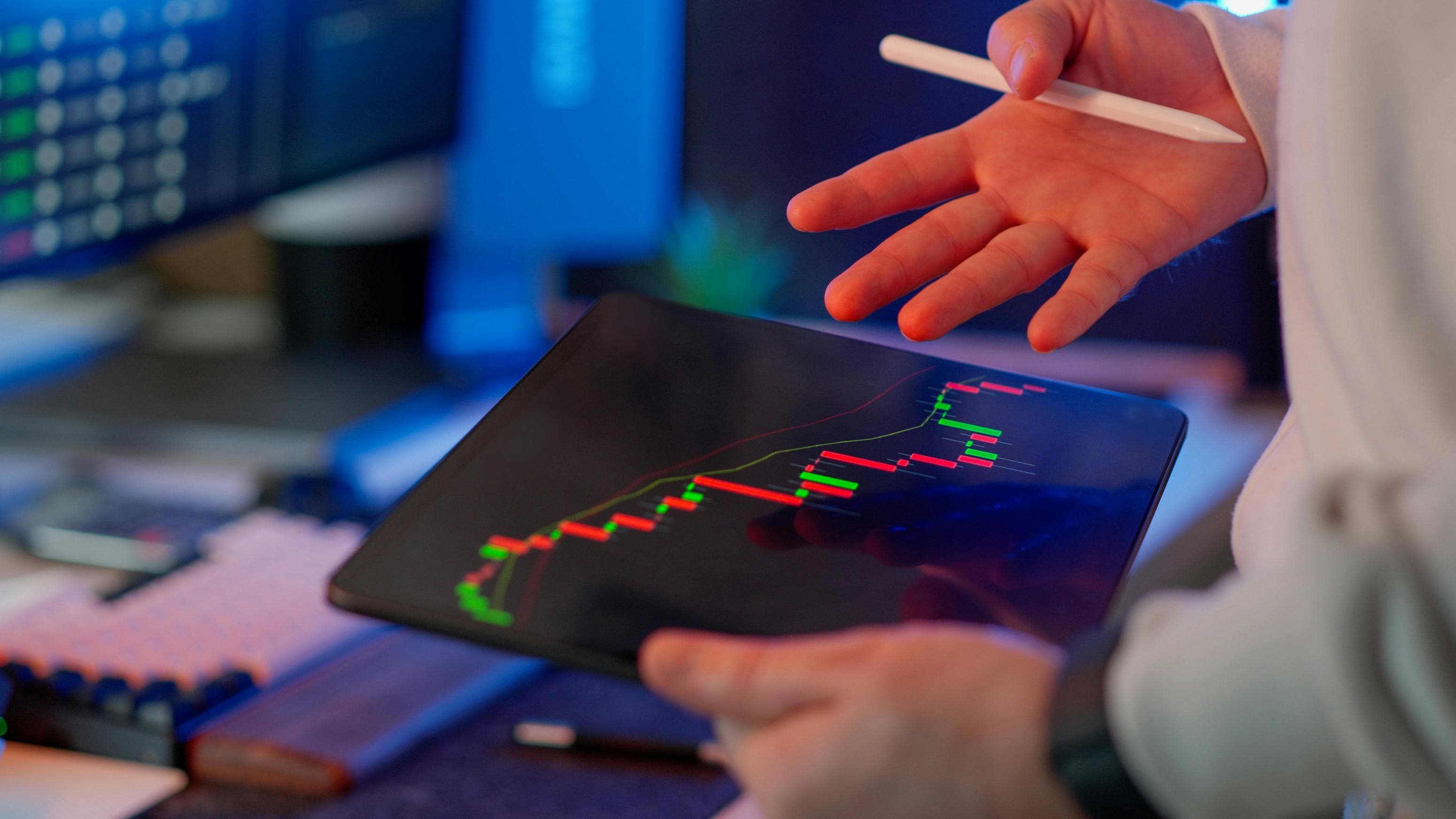 A trader analysing a candlestick chart on a tablet with a stylus